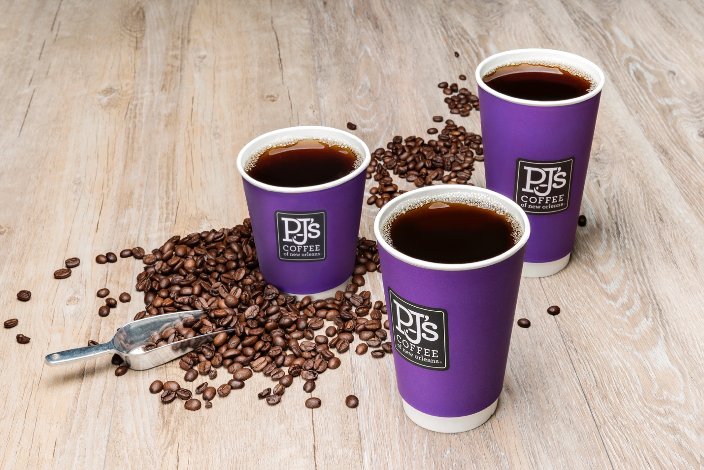 A group of purple cups of coffee next to coffee beans

Description automatically generated