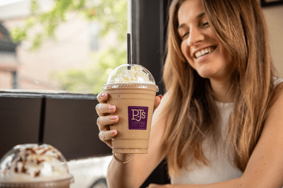 Woman smiling while holding PJ's Coffee drink